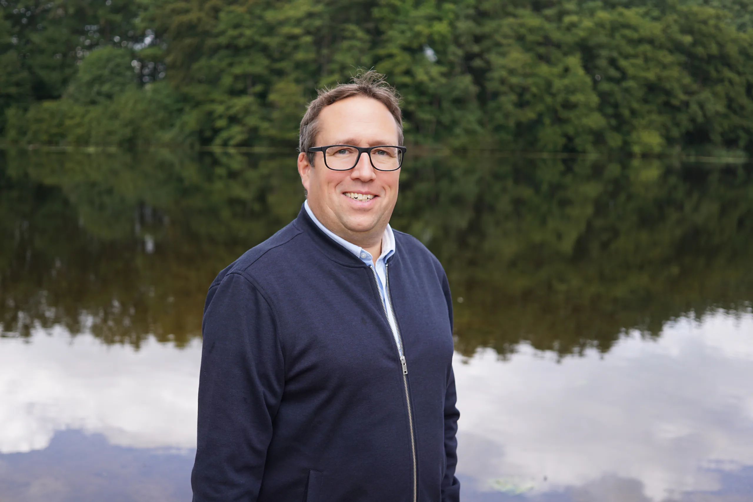 Björn Tessin blickt am Seeufer lächelnd in die Kamera